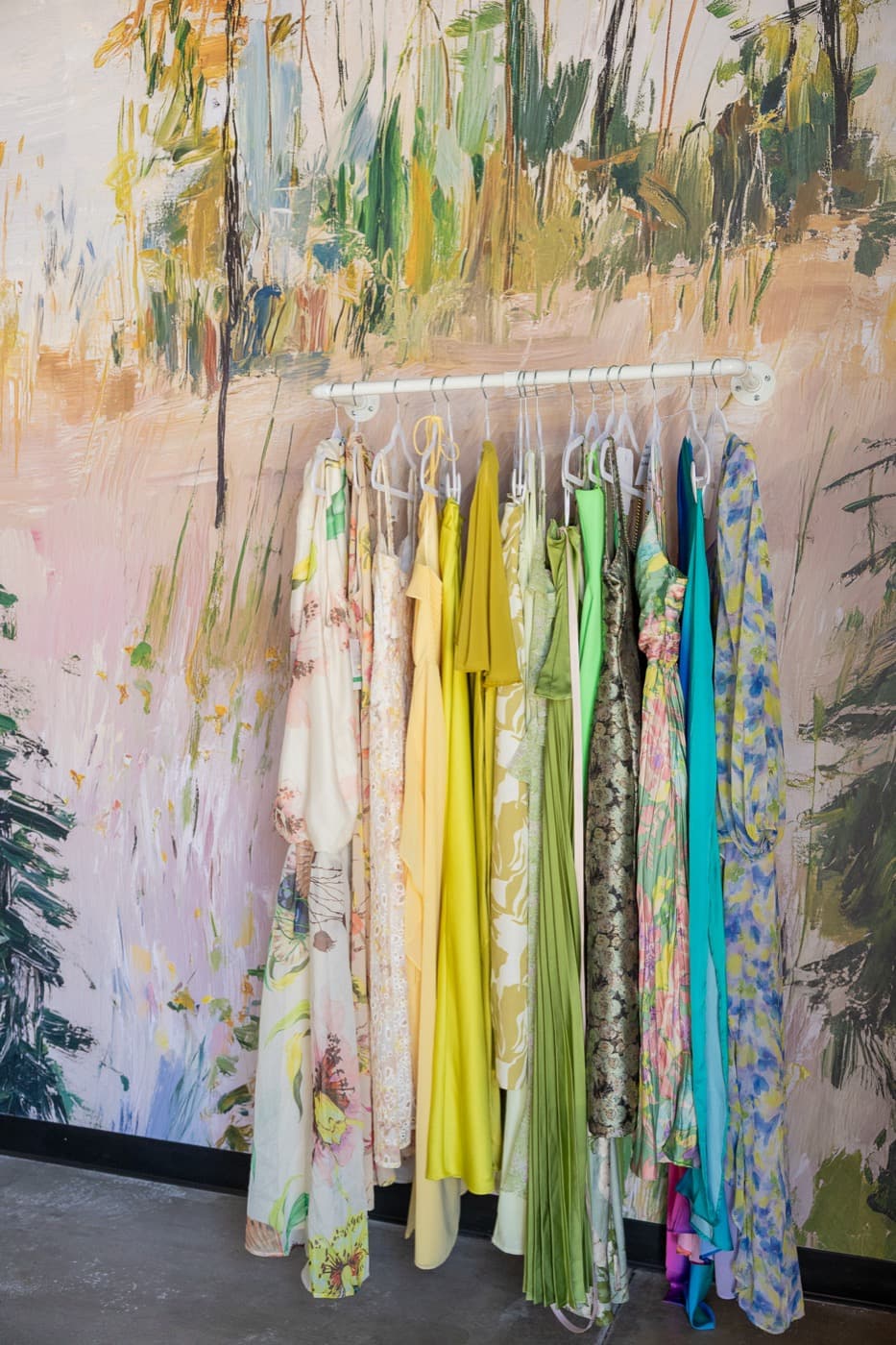Dresses arranged by color against the forest mural
