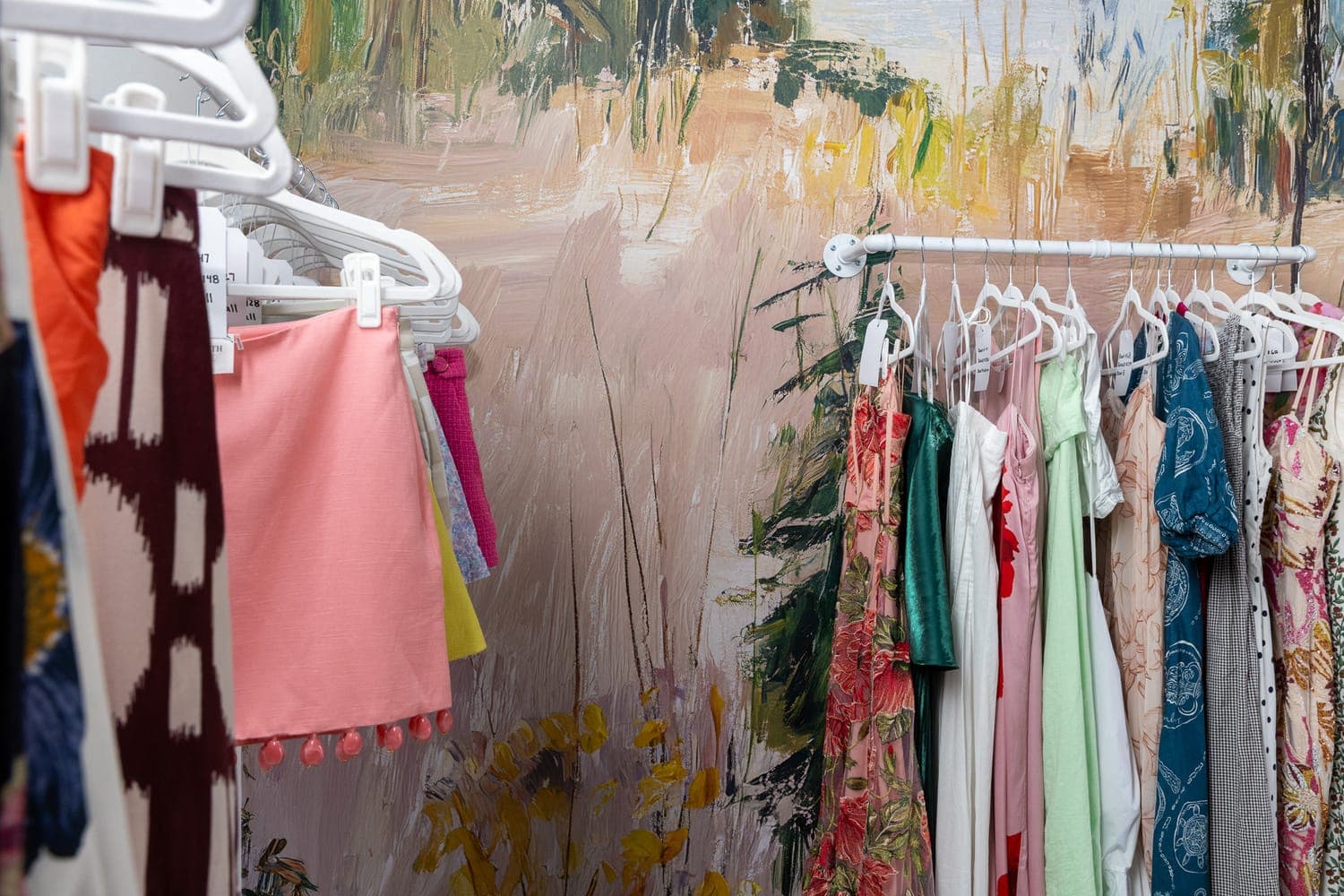 Racks of curated dresses against the Lemon Park wallpaper at the BORROW studio